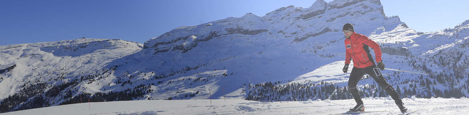 Flaine - A skier practising Nordic skating on a snow-covered groomed run, with the Flaine ski area in the background.